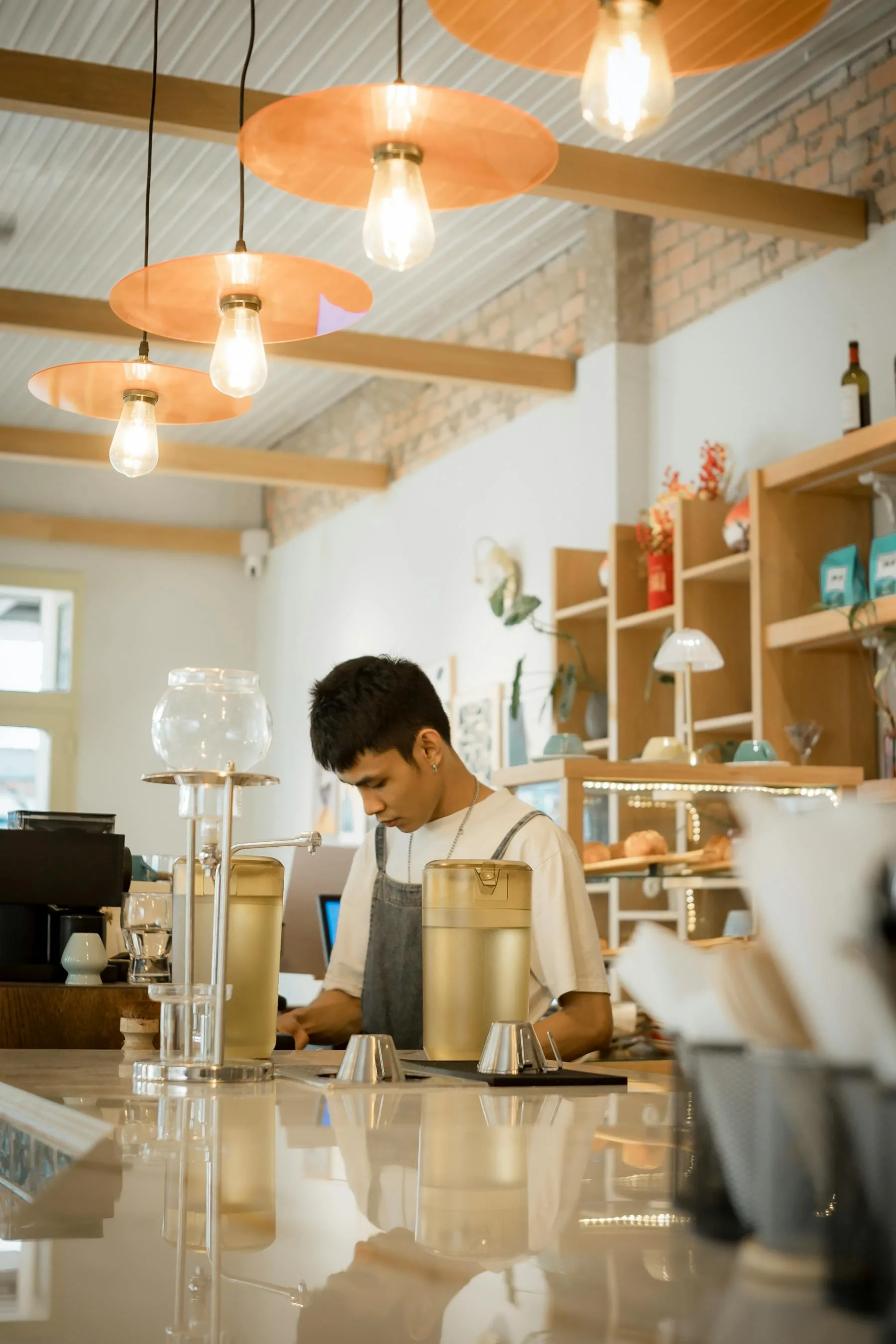 Barista working behind the counter in a warm modern coffee shop